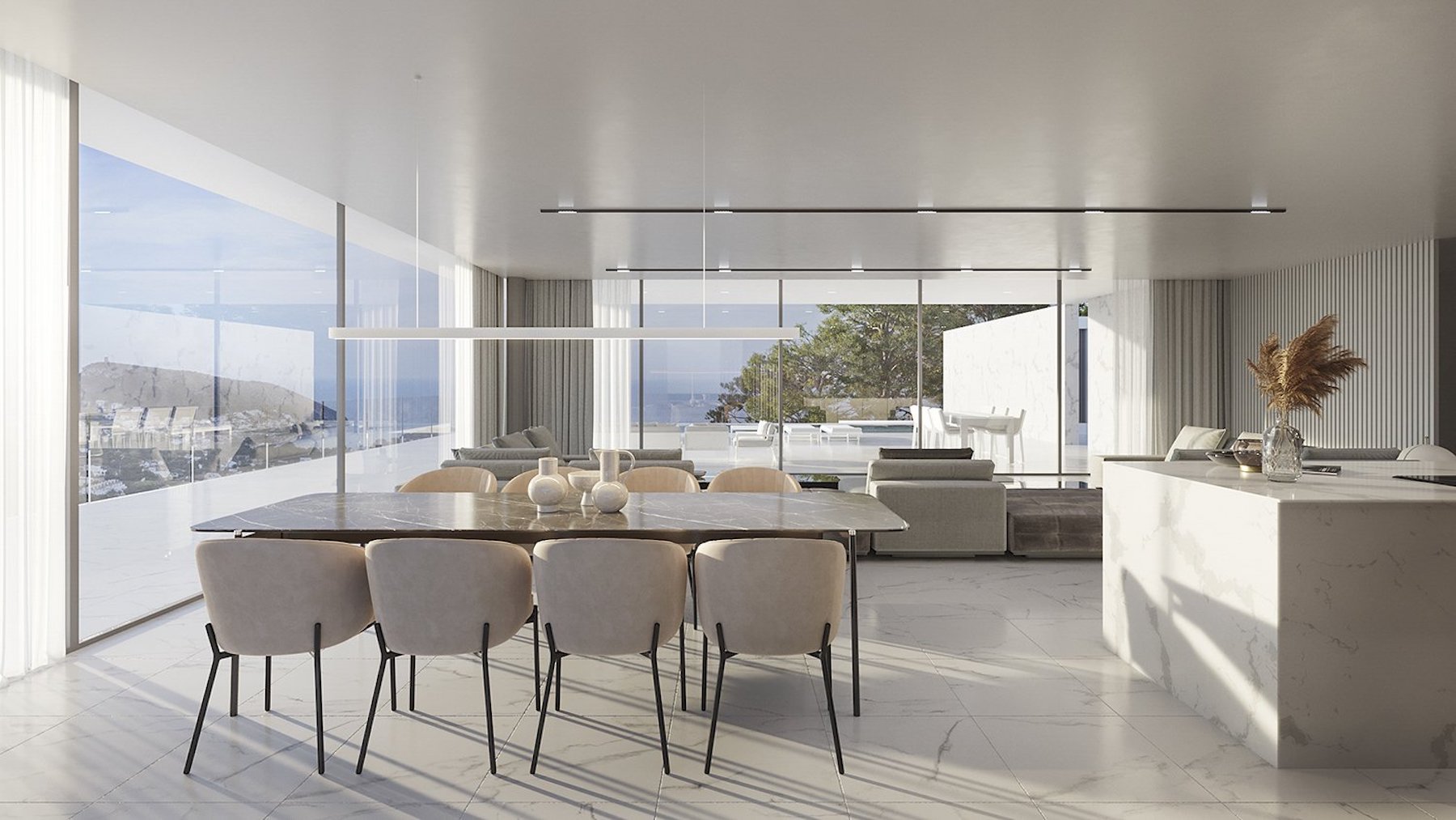 Salón-comedor diáfano con mesa de mármol oscuro, isla de cocina en piedra blanca y amplios ventanales que ofrecen vistas panorámicas al mar y la costa.