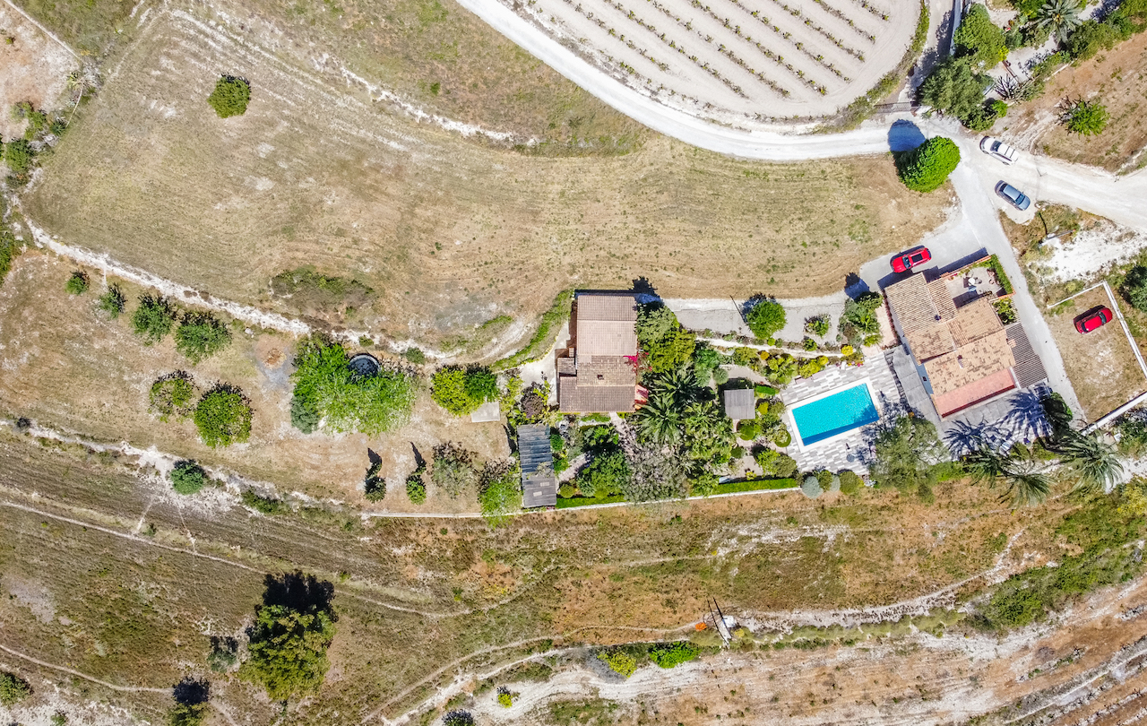 Vista aérea de la propiedad que muestra la distribución de las dos viviendas, la piscina con terraza y los jardines maduros integrados en el paisaje rural.
