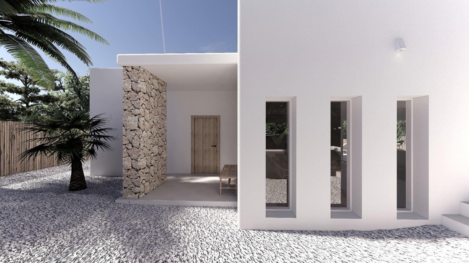 Entrada principal con fachada blanca, muro de piedra natural y ventanales verticales. El suelo de grava blanca y la vegetación mediterránea definen este acceso minimalista.