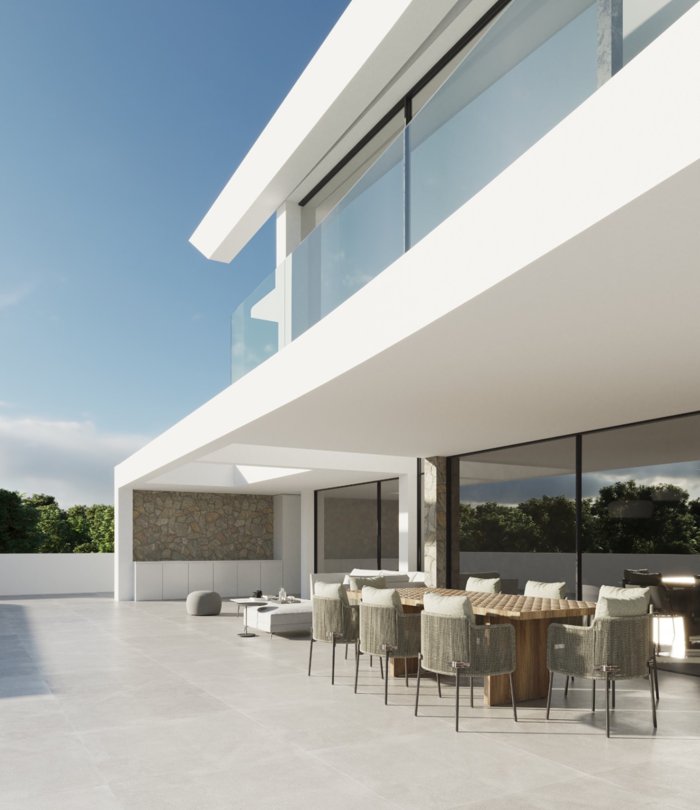 Terraza exterior con comedor de madera y sillas de cuerda trenzada bajo un voladizo minimalista, con paredes de piedra natural y barandillas de cristal.