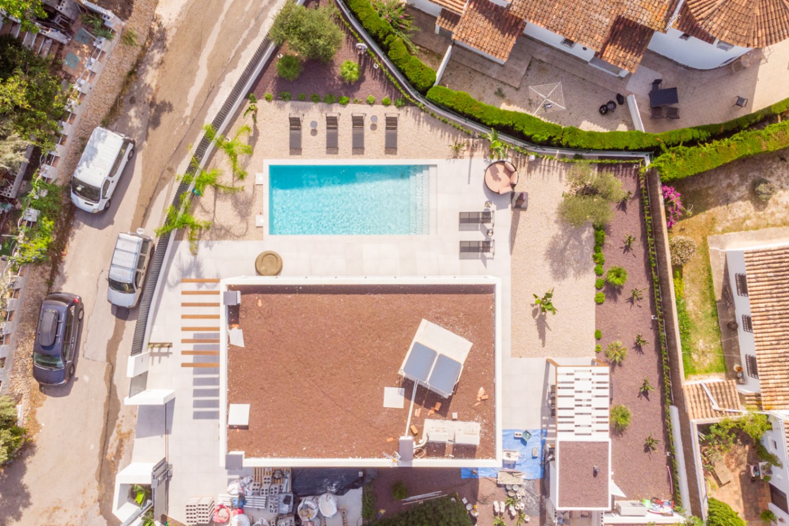 Vista aérea de la villa con piscina rectangular, solárium y jardín mediterráneo.