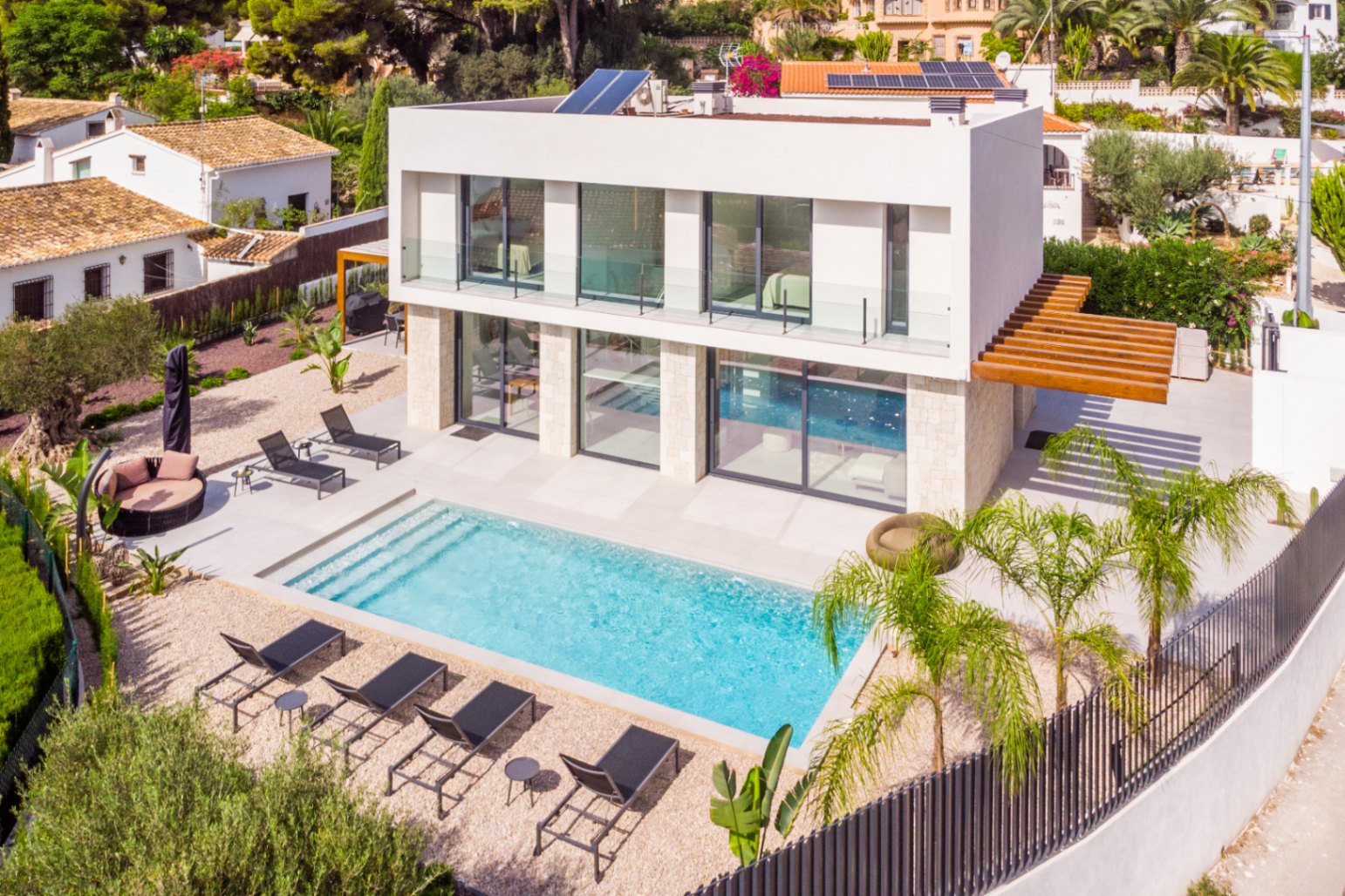 Vista aérea de la villa con piscina turquesa, rodeada de tumbonas y grava clara.