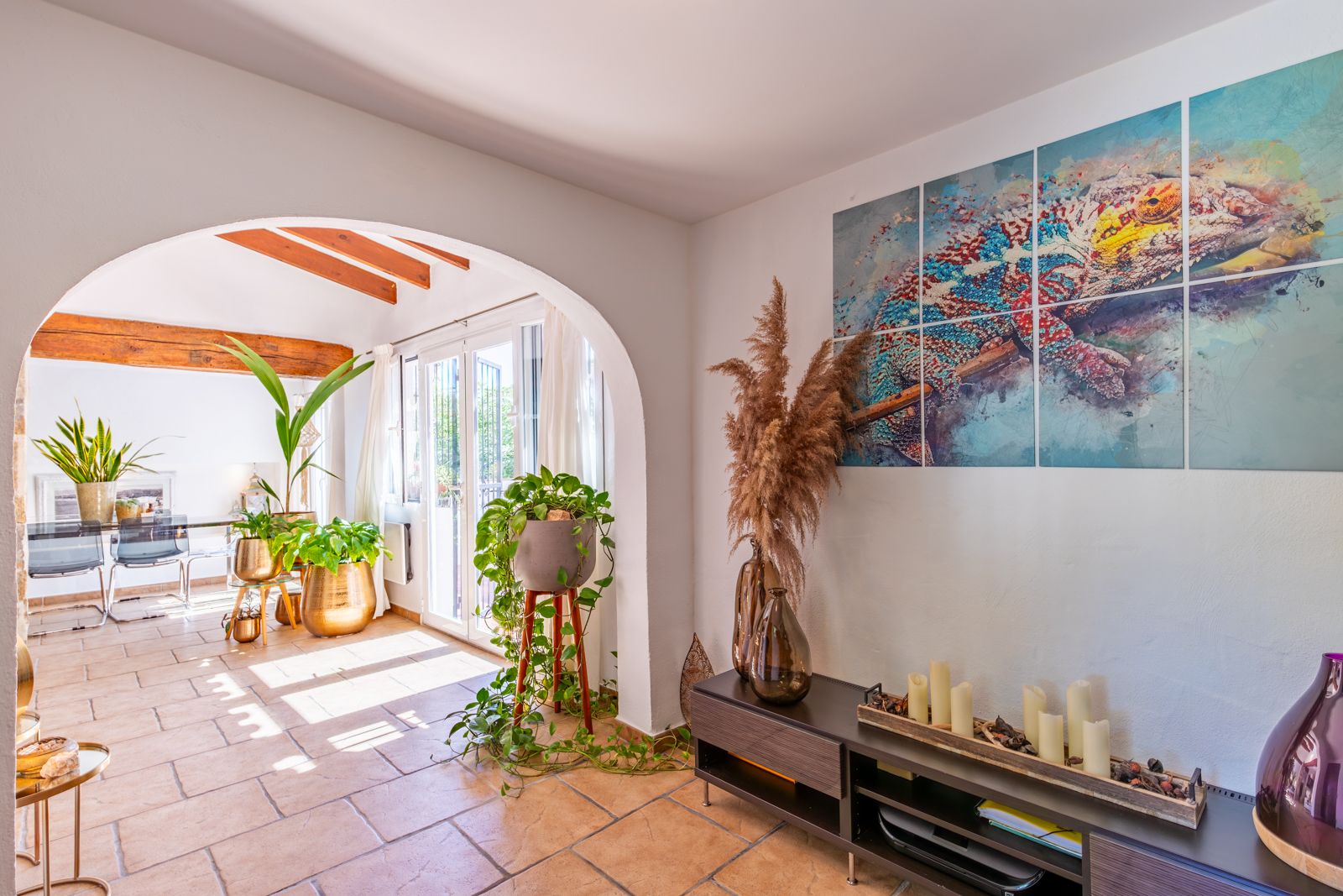 Salón de concepto abierto con arco de medio punto, suelos de gres rústico y vigas de madera vistas. Destaca la decoración contemporánea y la abundante luz natural.