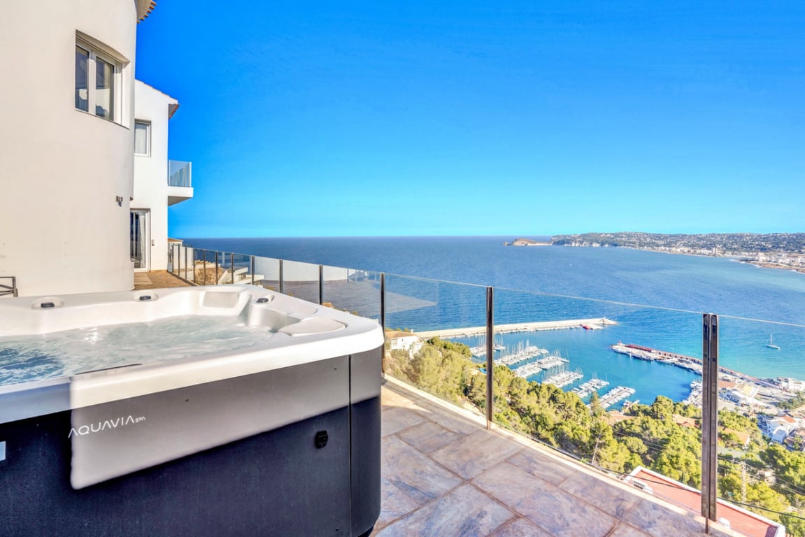 Jacuzzi exterior Aquavia Spa situado en terraza con suelo de piedra y barandilla de cristal, con vistas panorámicas al puerto de Jávea y al mar Mediterráneo.