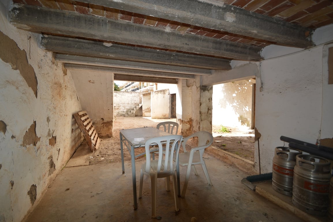 Área de porche cubierto con vigas de hormigón y bovedillas de ladrillo visto, conectando directamente con el patio exterior privado.
