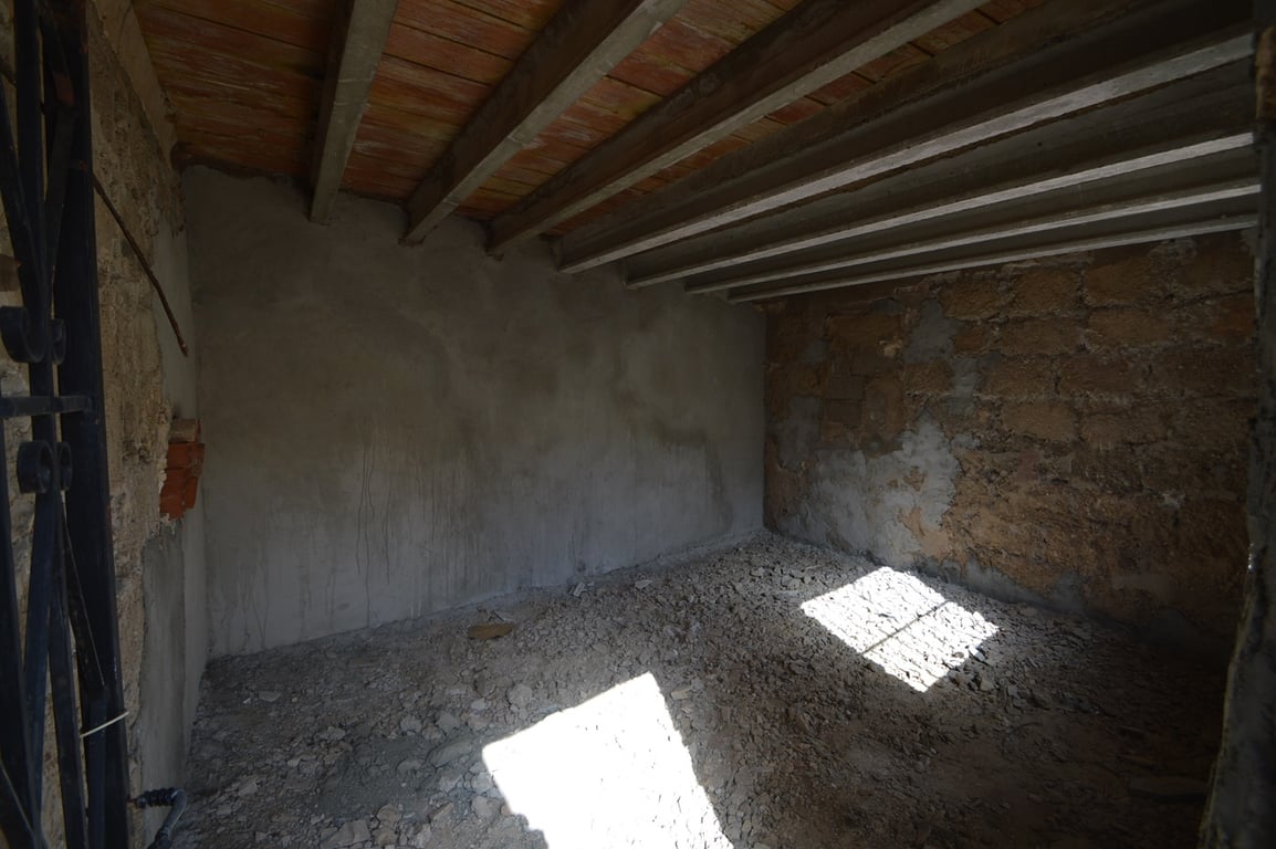 Espacio diáfano para reformar con muros de piedra original, vigas de madera a la vista y acceso lateral, ideal como trastero, taller o área de hobby.