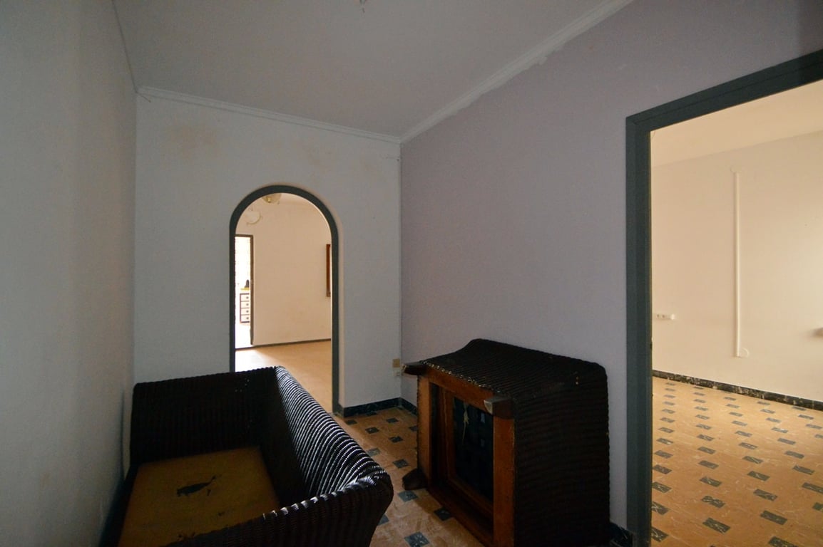 Habitación de paso con suelos de baldosas hidráulicas originales, un arco de medio punto y acceso a estancias contiguas con luz natural.