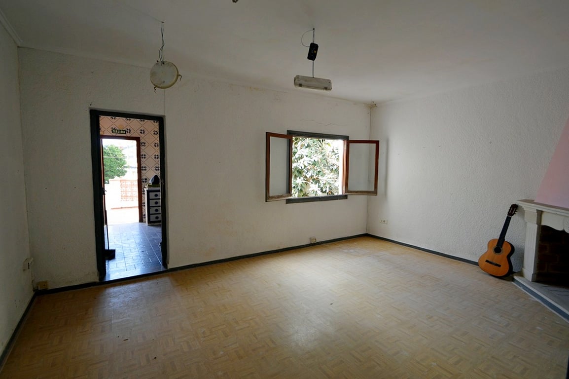 Salón comedor con chimenea, suelos con patrón de madera y ventana al exterior. La estancia ofrece acceso directo a la zona de terraza y cocina.