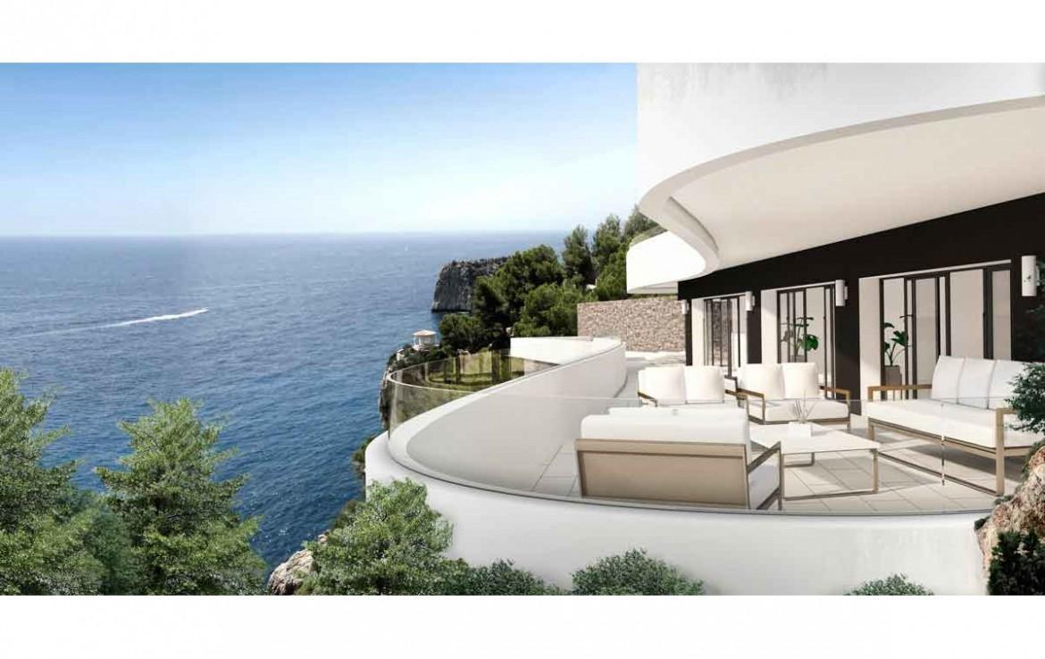 Terraza curva con barandilla de cristal y mobiliario de diseño, ofreciendo vistas panorámicas al mar Mediterráneo y los acantilados de Jávea.