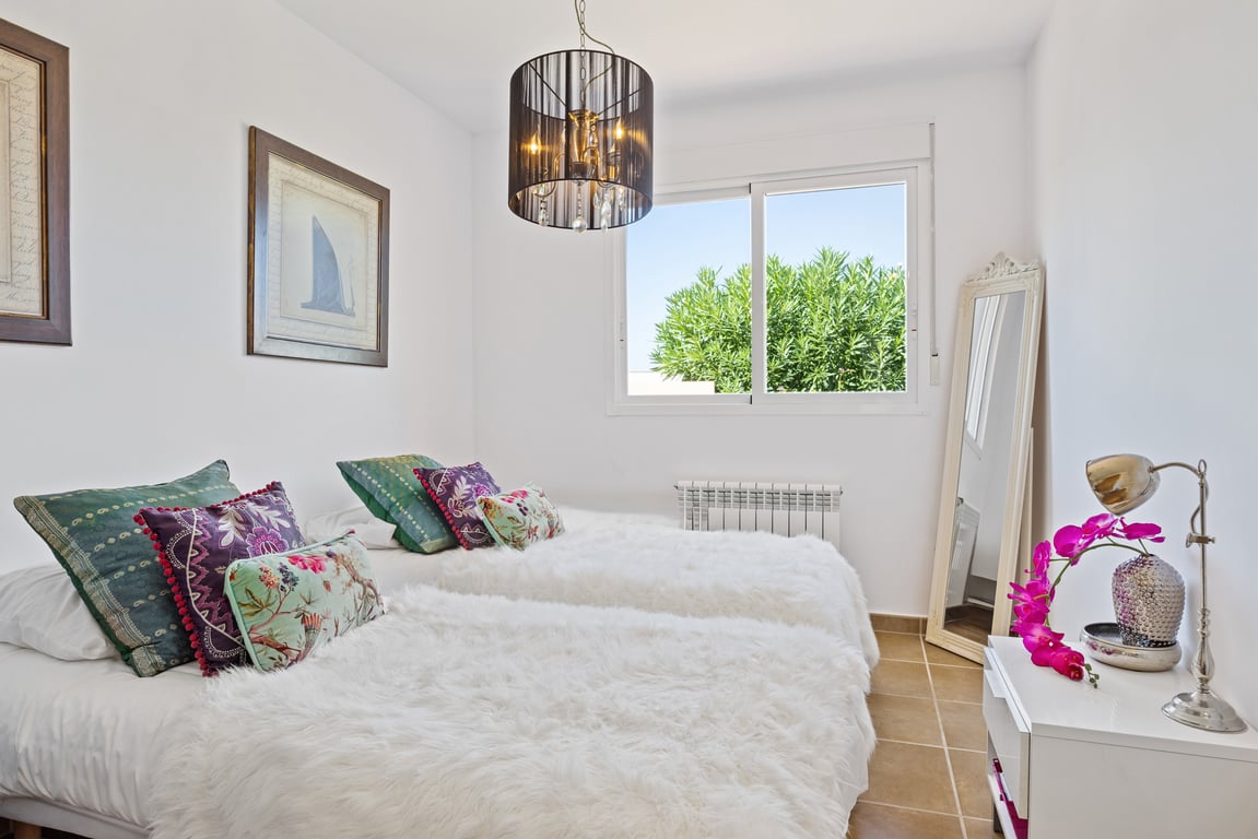 Dormitorio luminoso con dos camas individuales, suelos de gres y un gran ventanal con vistas al jardín. Dispone de calefacción central y una lámpara de techo de diseño.