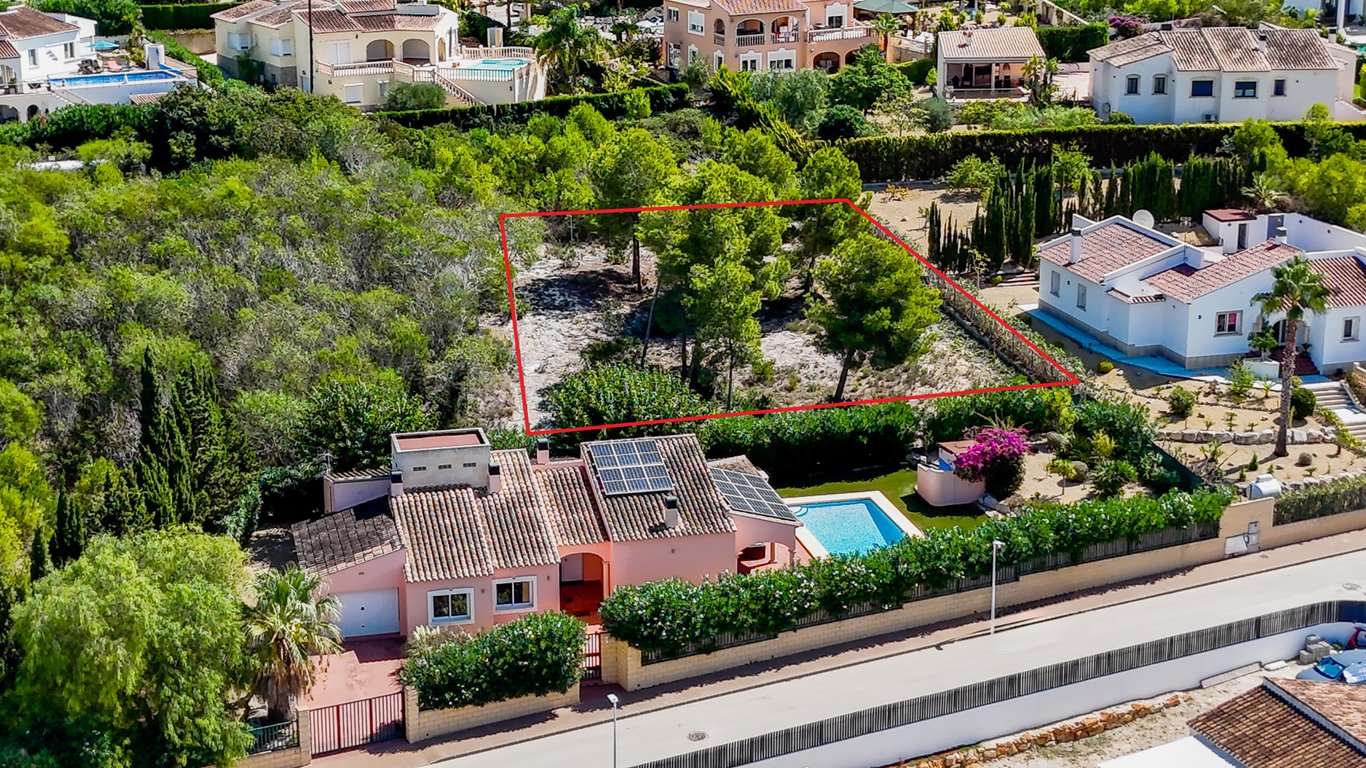 Vista aérea de la villa con paneles solares y piscina, destacando la parcela urbana colindante delimitada en rojo para futura construcción.