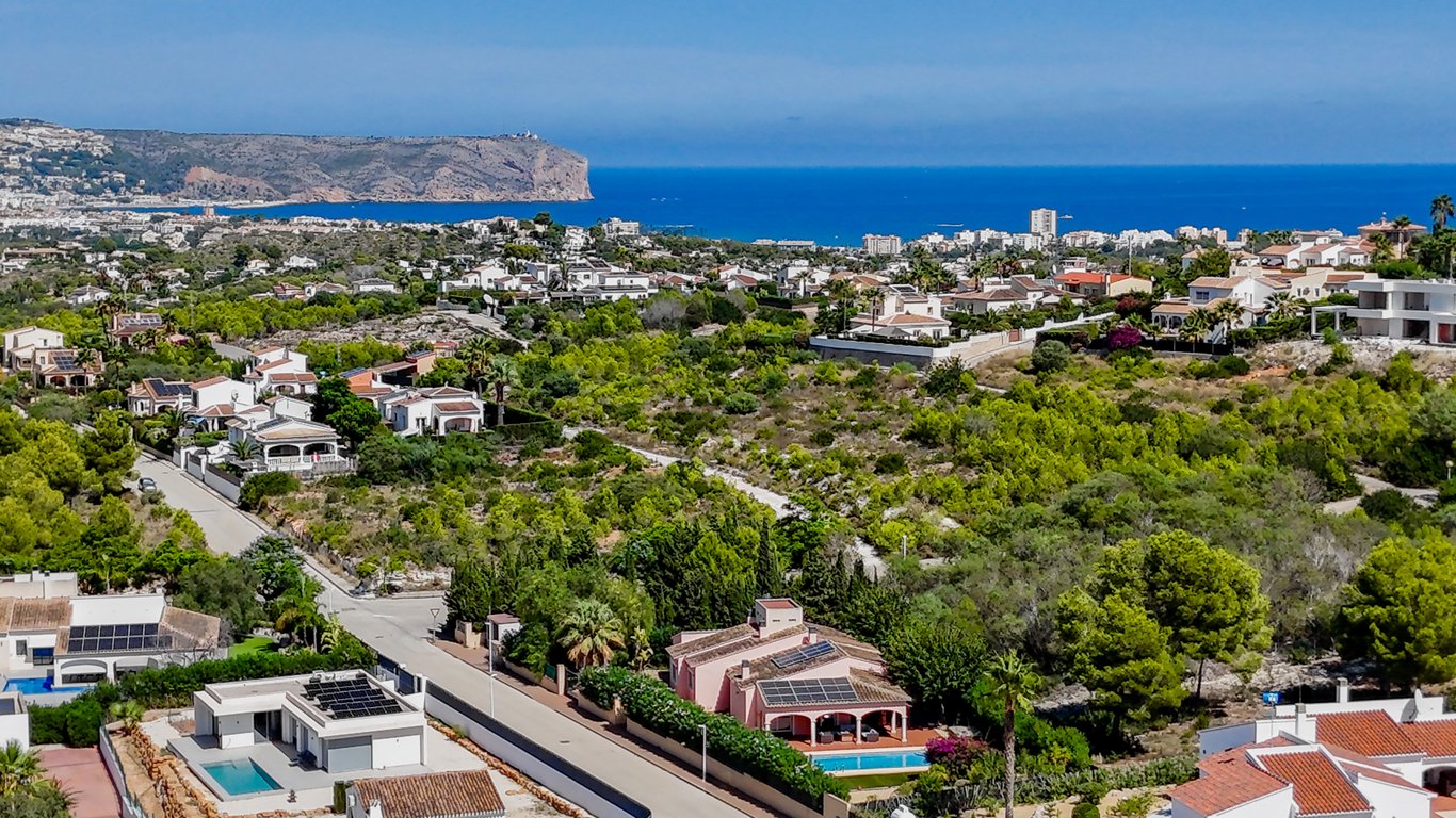 Vista aérea panorámica de la villa y su entorno residencial en Jávea, destacando la proximidad al mar Mediterráneo y las vistas despejadas hacia el cabo.