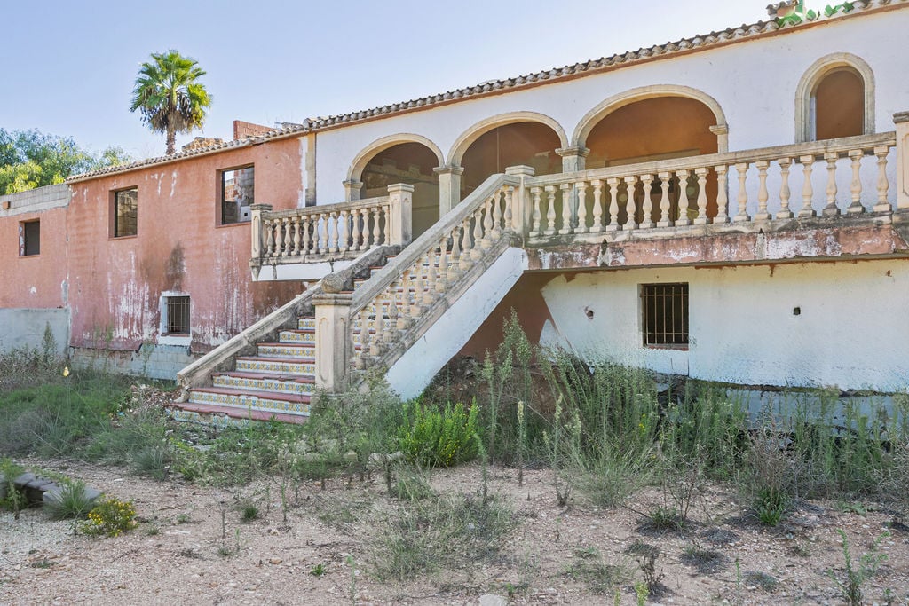 Fachada exterior con escalera de piedra señorial y naya de arcos de medio punto, destacando los azulejos tradicionales en los peldaños y la balaustrada.