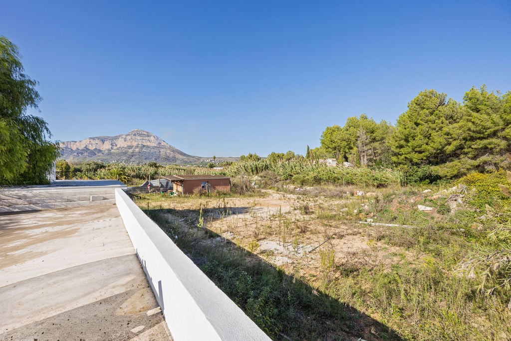 Vista panorámica del macizo del Montgó desde una plataforma elevada de hormigón, rodeada de vegetación mediterránea y una amplia parcela llana.