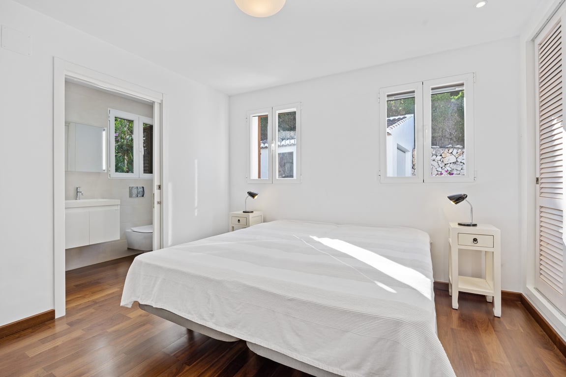 Dormitorio luminoso con suelo de madera, baño en suite modernizado y ventanas de doble acristalamiento que aportan abundante luz natural al espacio.