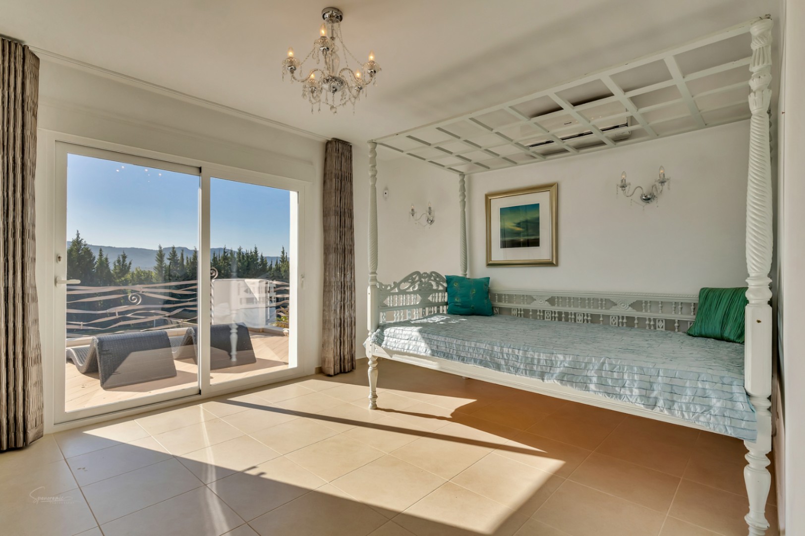 Dormitorio con cama de dosel tallada en blanco, acceso directo a la terraza privada y vistas despejadas al entorno natural del Montgó.