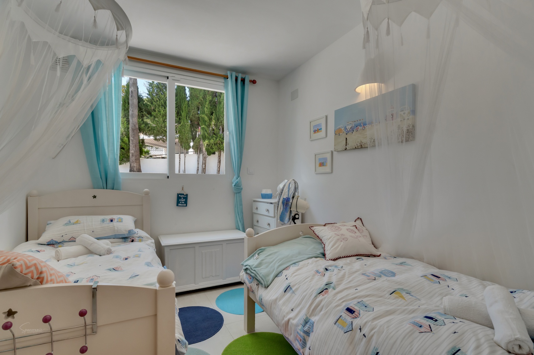Habitación infantil luminosa con dos camas individuales, decoración temática playera y vistas al exterior.