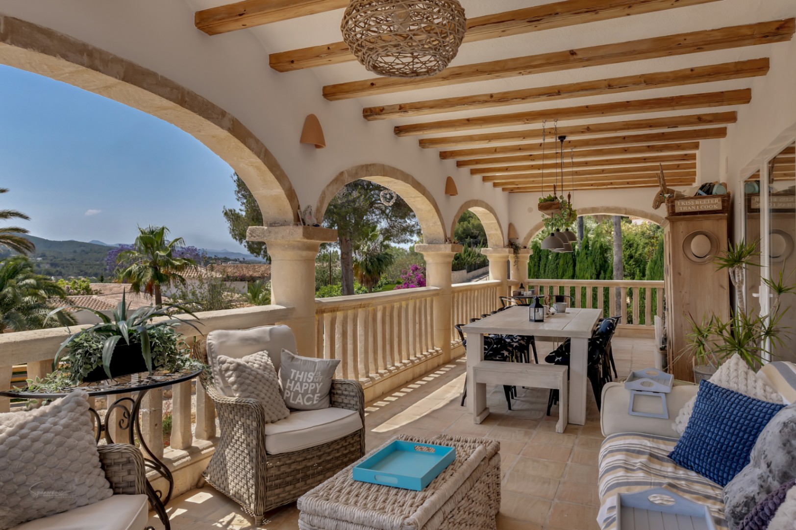 Terraza cubierta con arcos de piedra, vigas de madera y vistas panorámicas a la montaña.