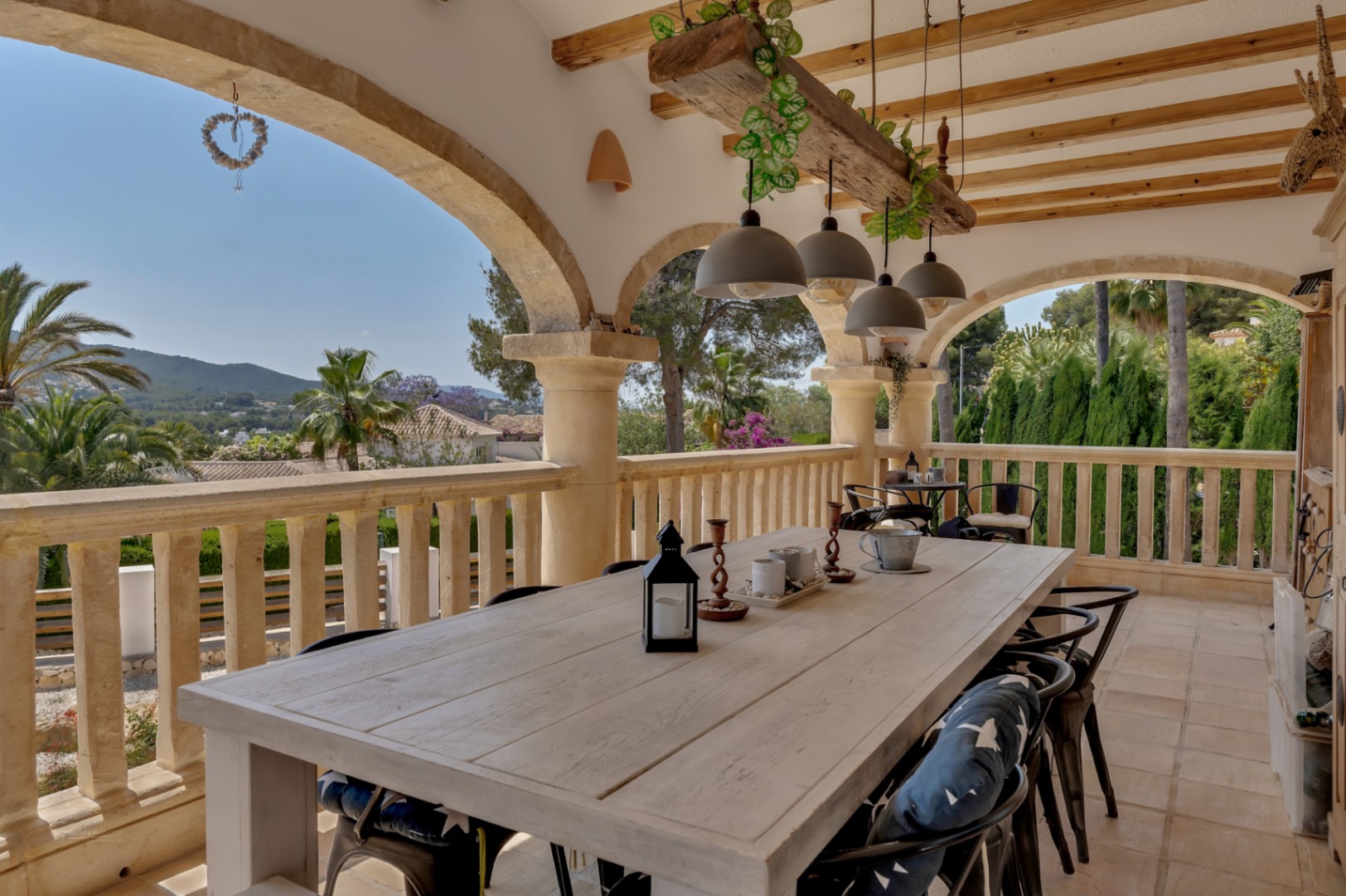 Terraza cubierta con mesa de comedor rústica y vistas a la vegetación.