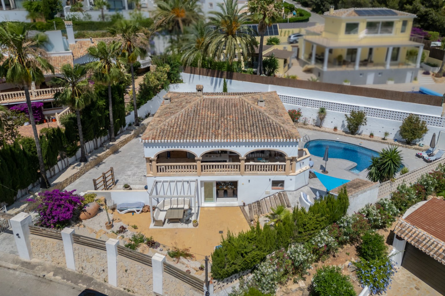 Vista aérea de la villa en Jávea con terraza cubierta, piscina azul y jardín mediterráneo.