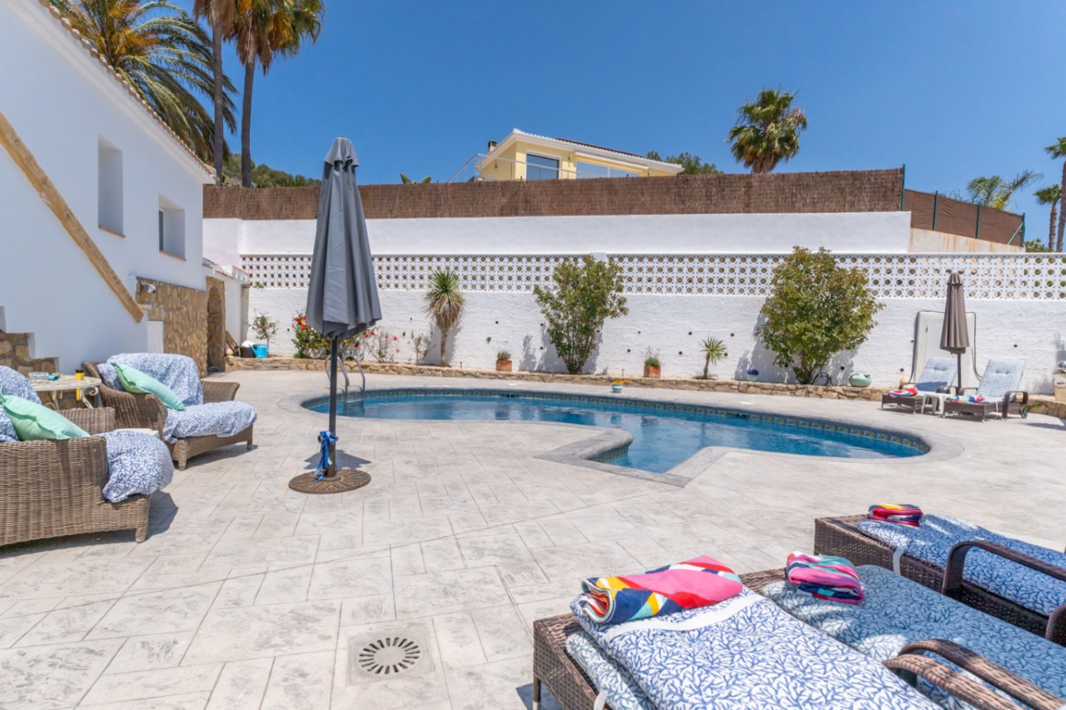 Vista de la piscina privada con tumbonas y zona de estar al aire libre en Jávea.