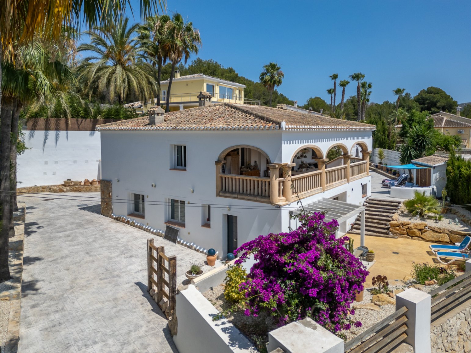Vista exterior de la villa en Jávea, destacando la terraza con arcos y la buganvilla florida.