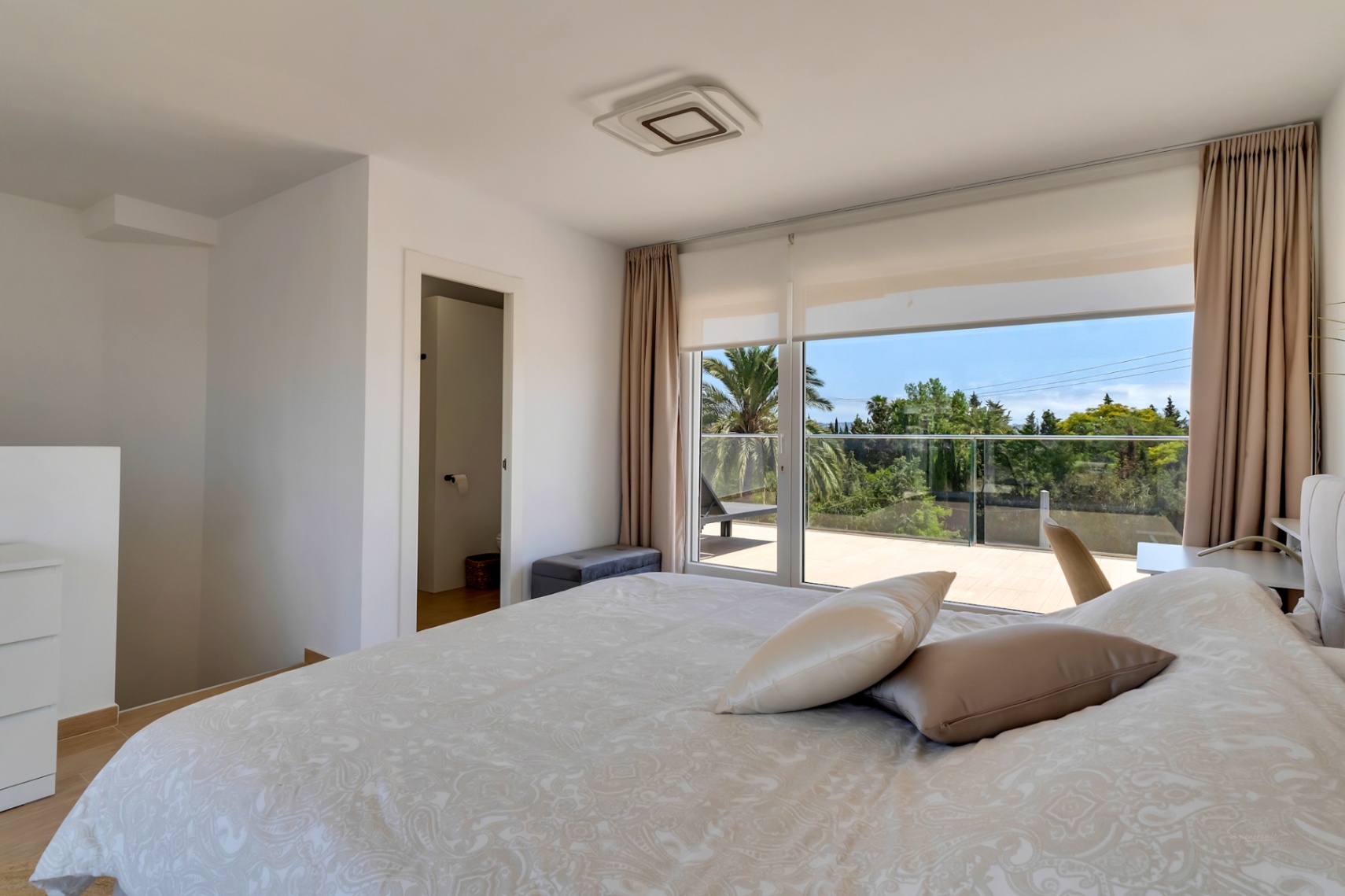Dormitorio luminoso con acceso directo a terraza privada y vistas al entorno natural. Incluye climatización por conductos, suelos de madera y baño en suite.