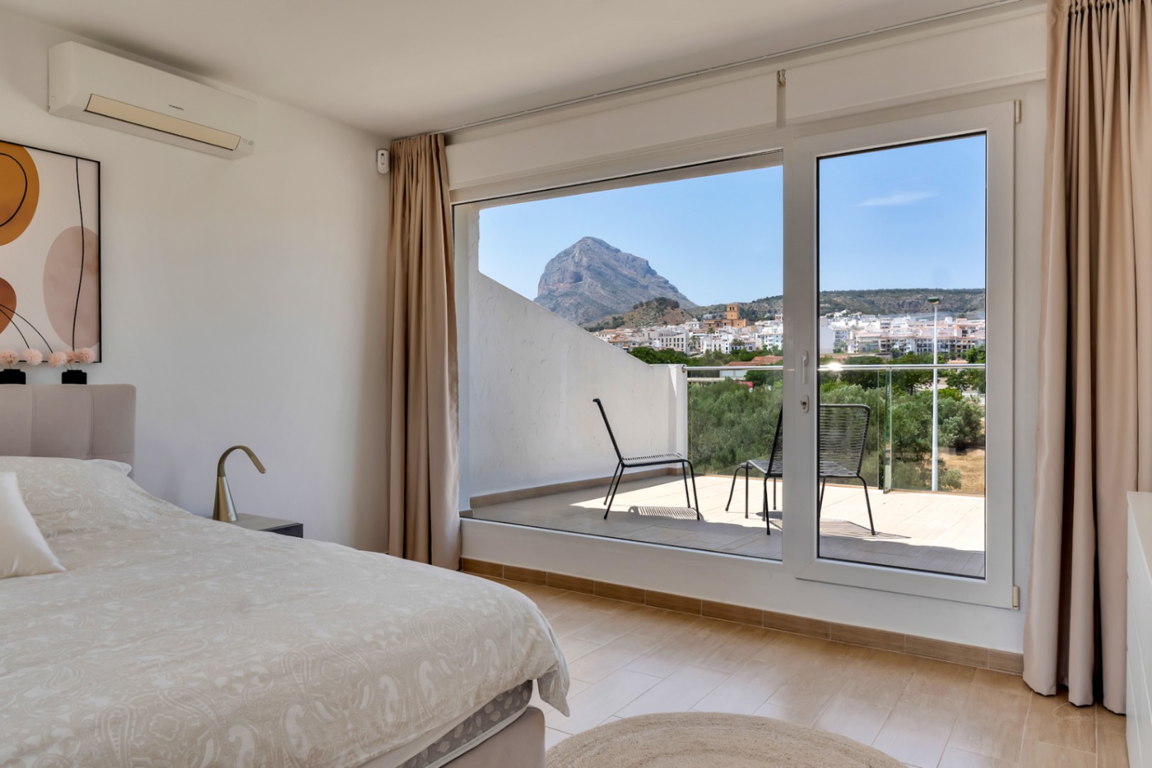 Dormitorio principal con acceso a terraza privada, ofreciendo vistas despejadas al Montgó y al casco antiguo. Incluye aire acondicionado y suelos de gres cerámico.