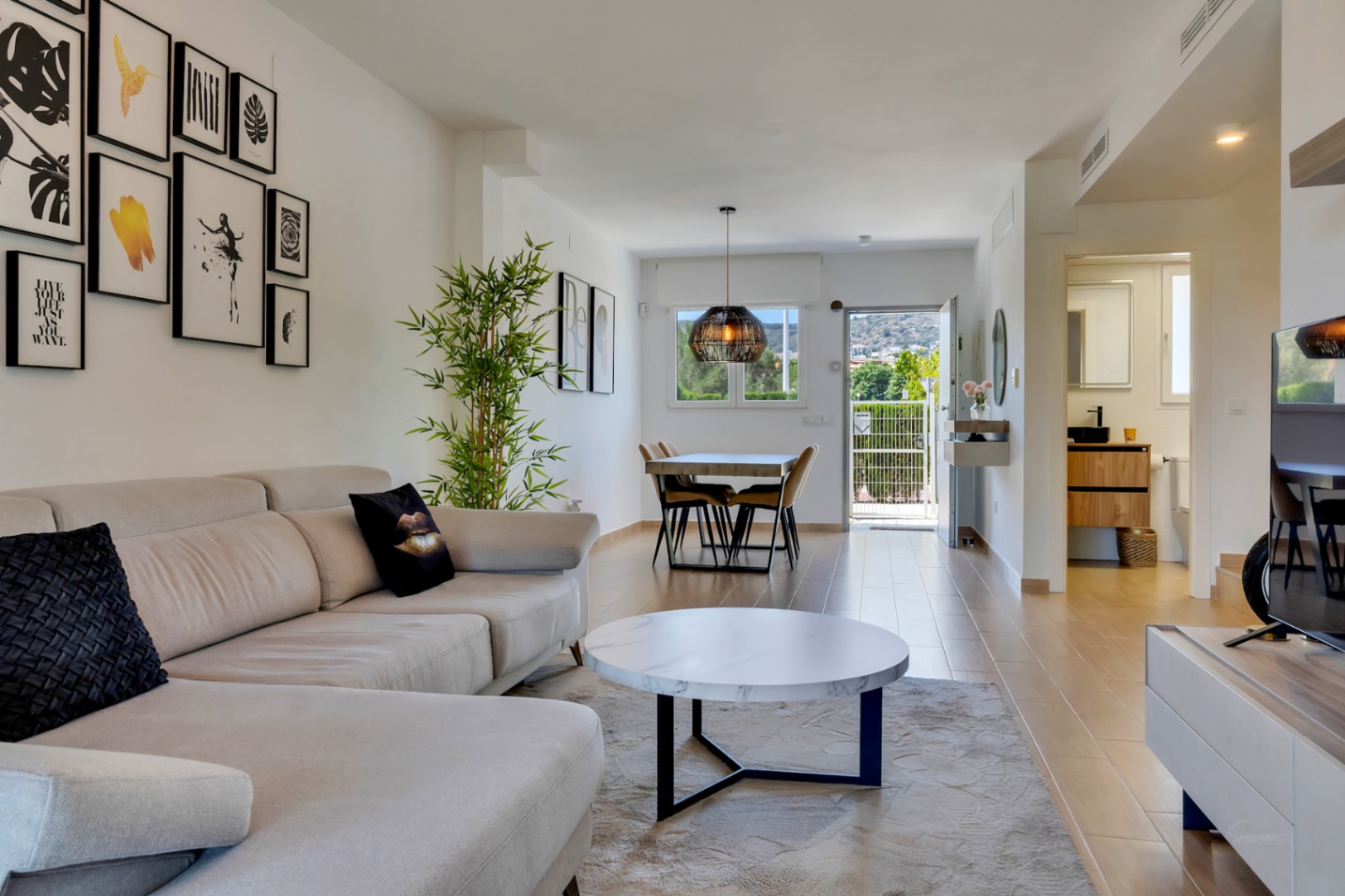 Salón comedor de concepto abierto con suelos cerámicos de imitación madera, mobiliario contemporáneo y acceso directo al exterior a través de una puerta acristalada.