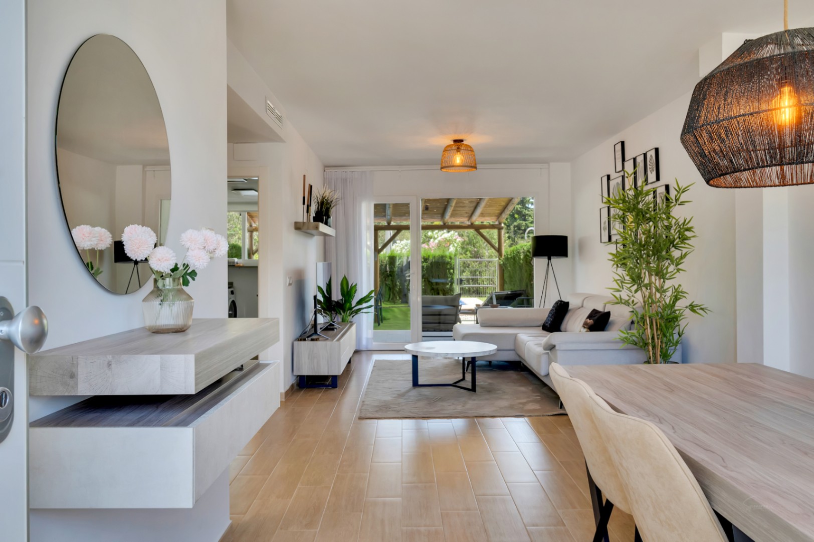 Salón-comedor de concepto abierto con suelos de gres efecto madera y acceso directo al patio privado. Destacan el mobiliario moderno y la abundante luz natural.