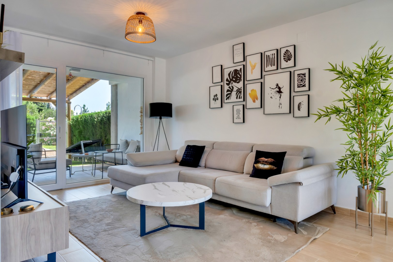 Salón luminoso con sofá rinconera, mesa de mármol y acceso directo al patio privado a través de grandes ventanales correderos.