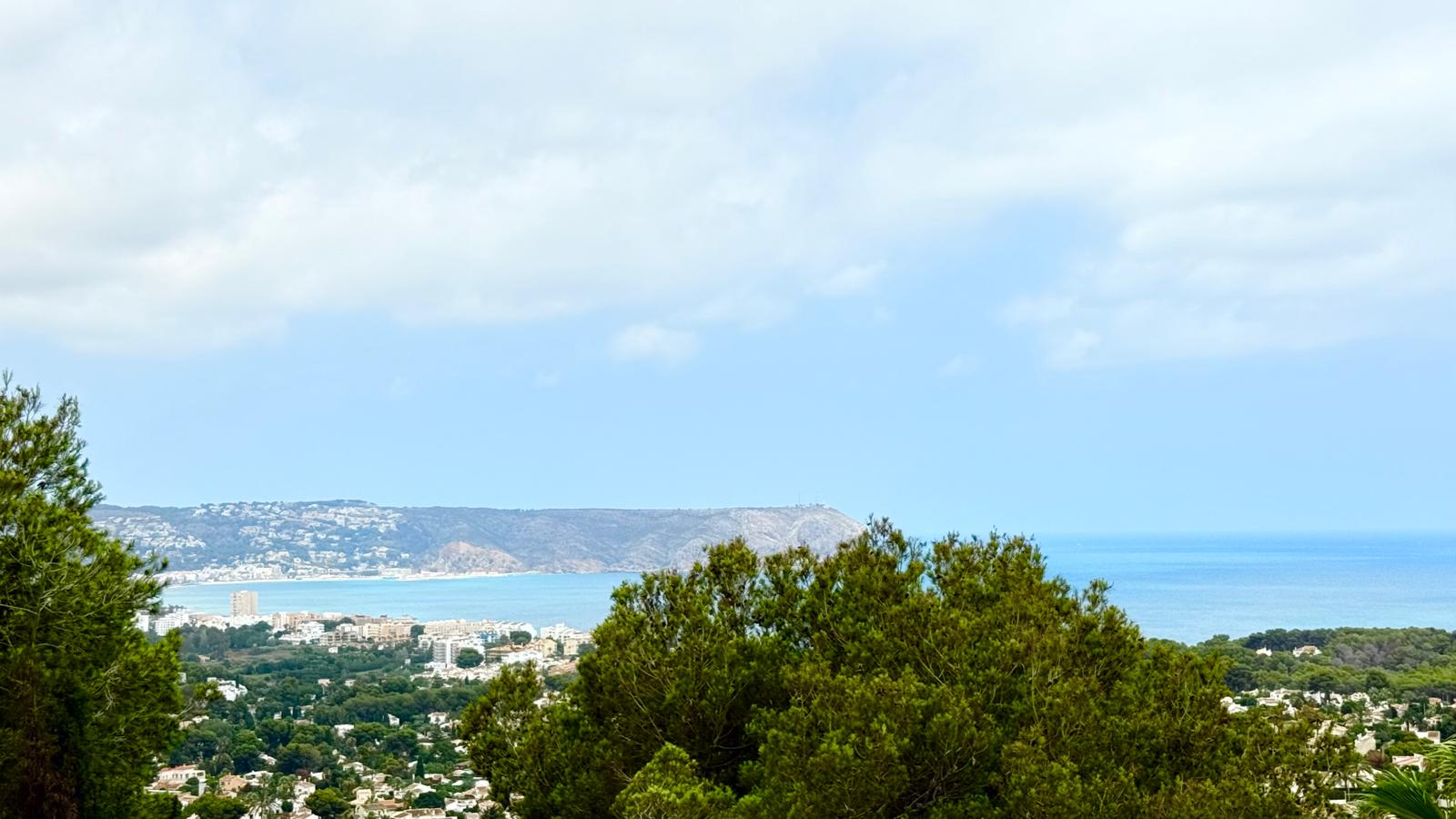 Vista panorámica de la bahía de Jávea y el Cabo de San Antonio, enmarcada por la vegetación mediterránea desde la posición elevada de la propiedad.