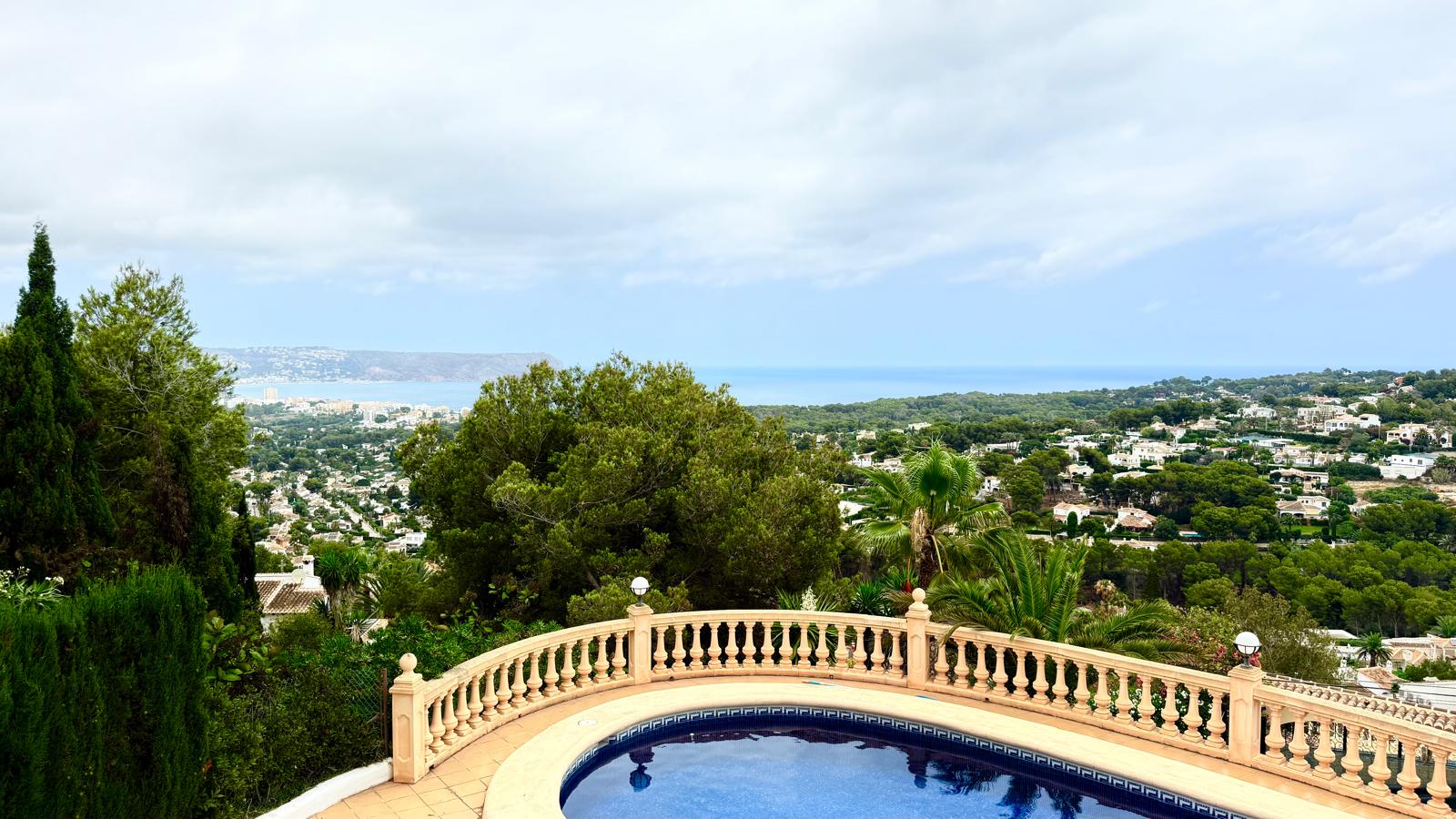 Vistas panorámicas al mar Mediterráneo y a la bahía de Jávea desde la terraza superior, delimitada por una balaustrada de piedra clásica sobre la zona de la piscina.