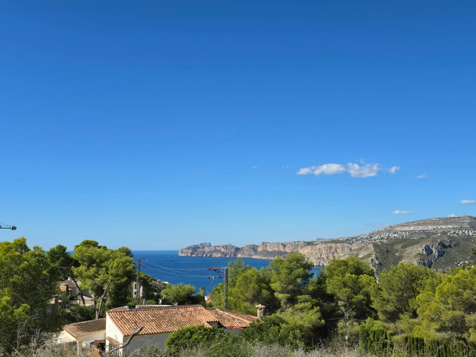 Vistas panorámicas al mar Mediterráneo y a los acantilados de Jávea desde la parcela elevada, rodeada de pinos y vegetación autóctona.