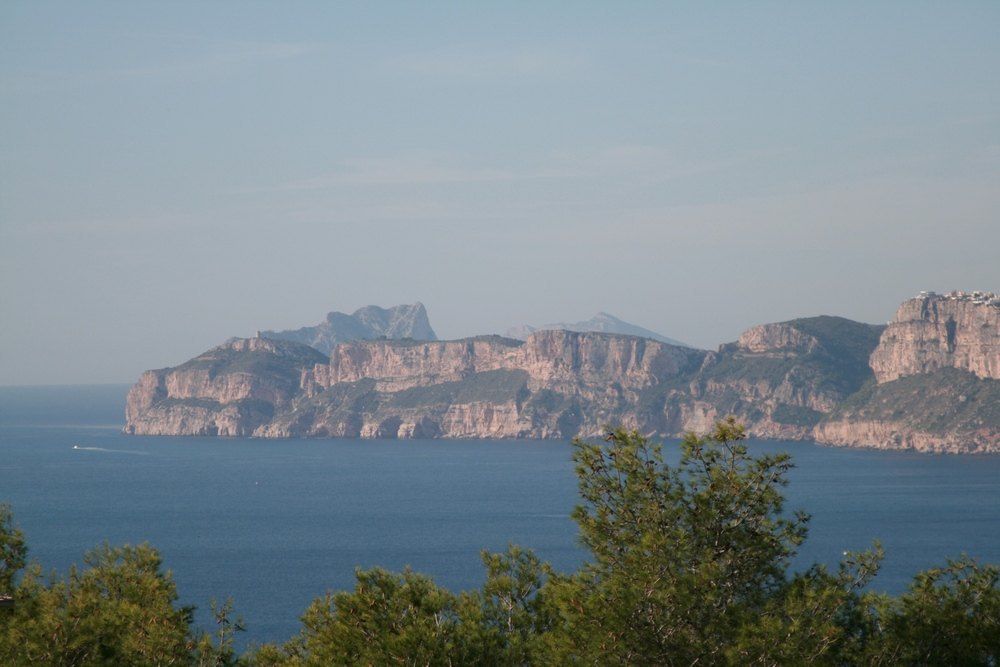 Vistas panorámicas al mar Mediterráneo y a los acantilados de la costa de Jávea desde la parcela, rodeada de vegetación autóctona y pinos.