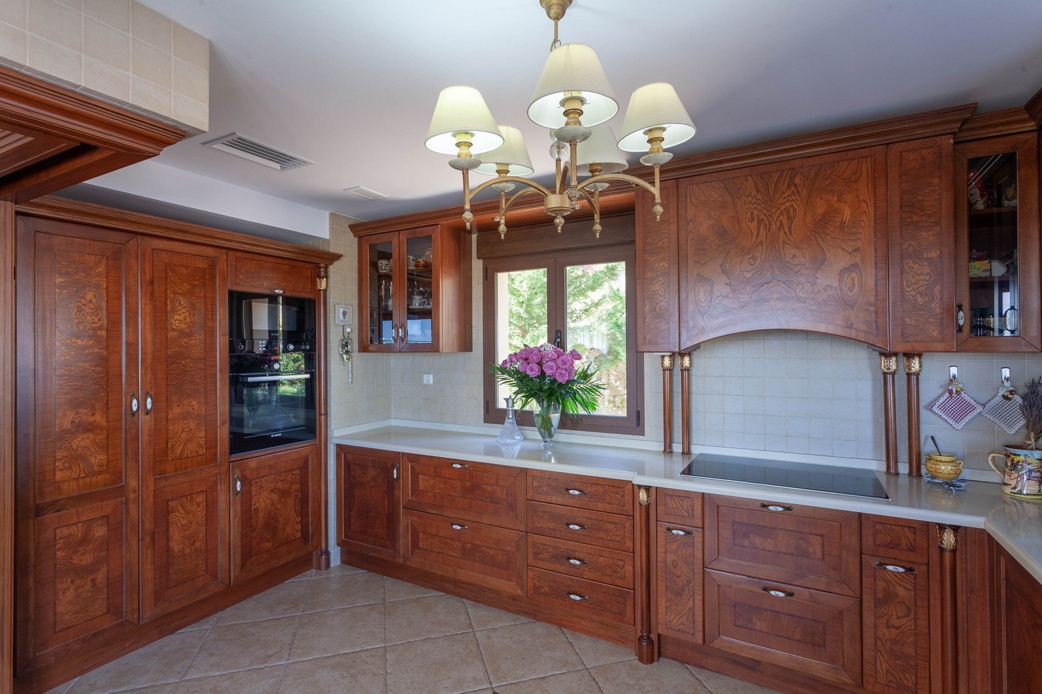 Cocina clásica con muebles de madera tallada y encimera de cuarzo blanco.