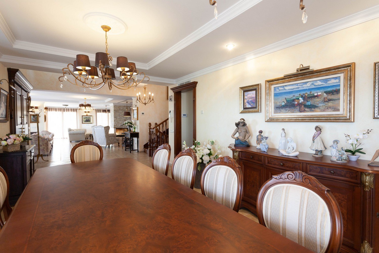 Comedor con mesa de madera oscura, sillas tapizadas y aparador clásico con esculturas decorativas.