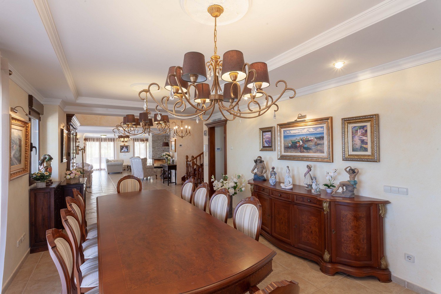 Comedor formal con mesa de madera oscura, sillas tapizadas y aparador clásico con adornos dorados.