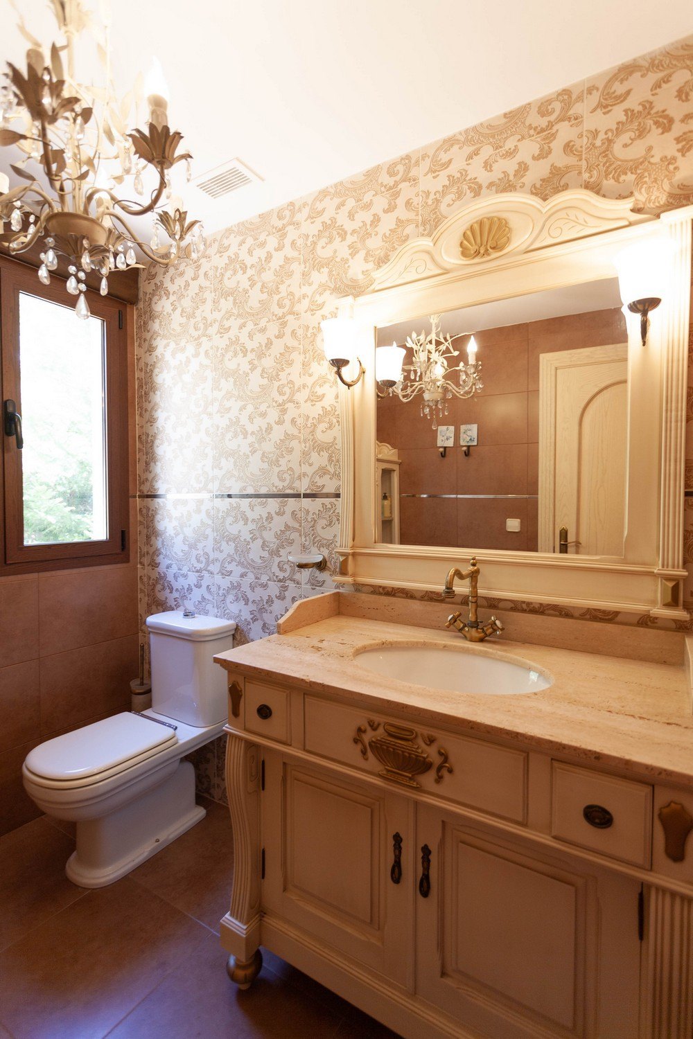 Detalle de baño de estilo clásico con tocador de mármol y papel tapiz floral.