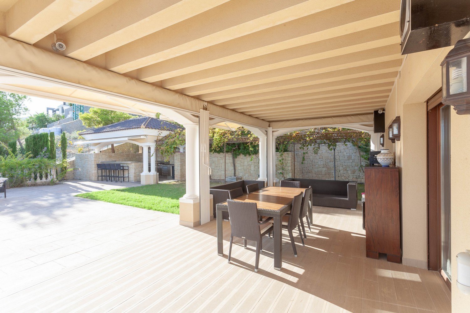 Terraza cubierta con comedor y vistas al jardín con barbacoa en Benissa, Costa Blanca.