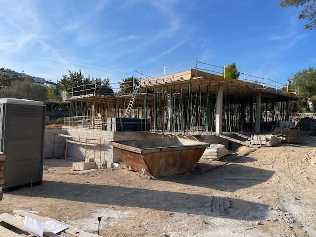 Villa en construcción en Moraira. Se observan los cimientos, columnas de soporte y encofrado del techo en un día soleado.