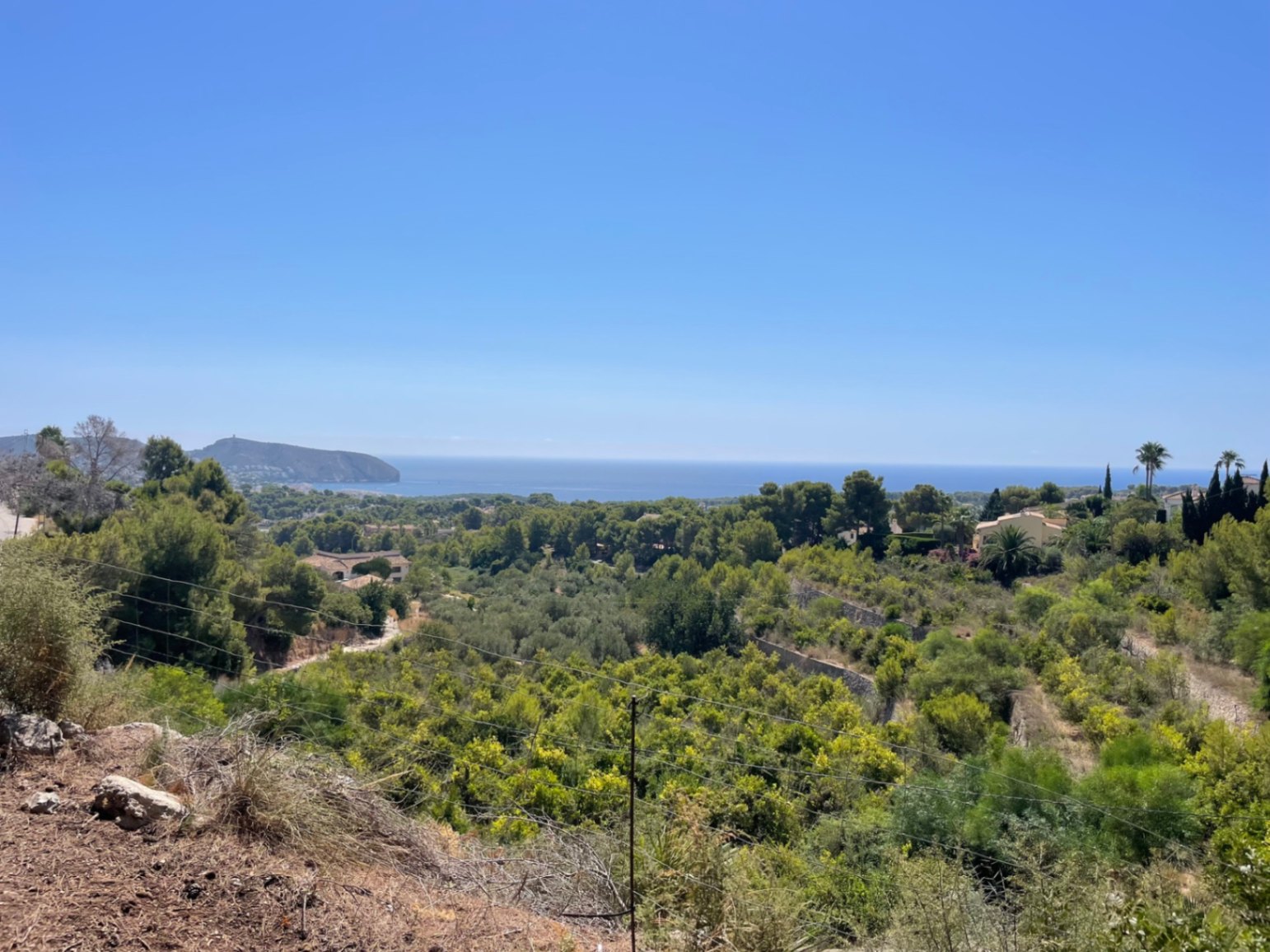 Vista panorámica desde la parcela elevada hacia el mar Mediterráneo, rodeada de vegetación autóctona y pinos en la zona de Benimeit, Moraira.