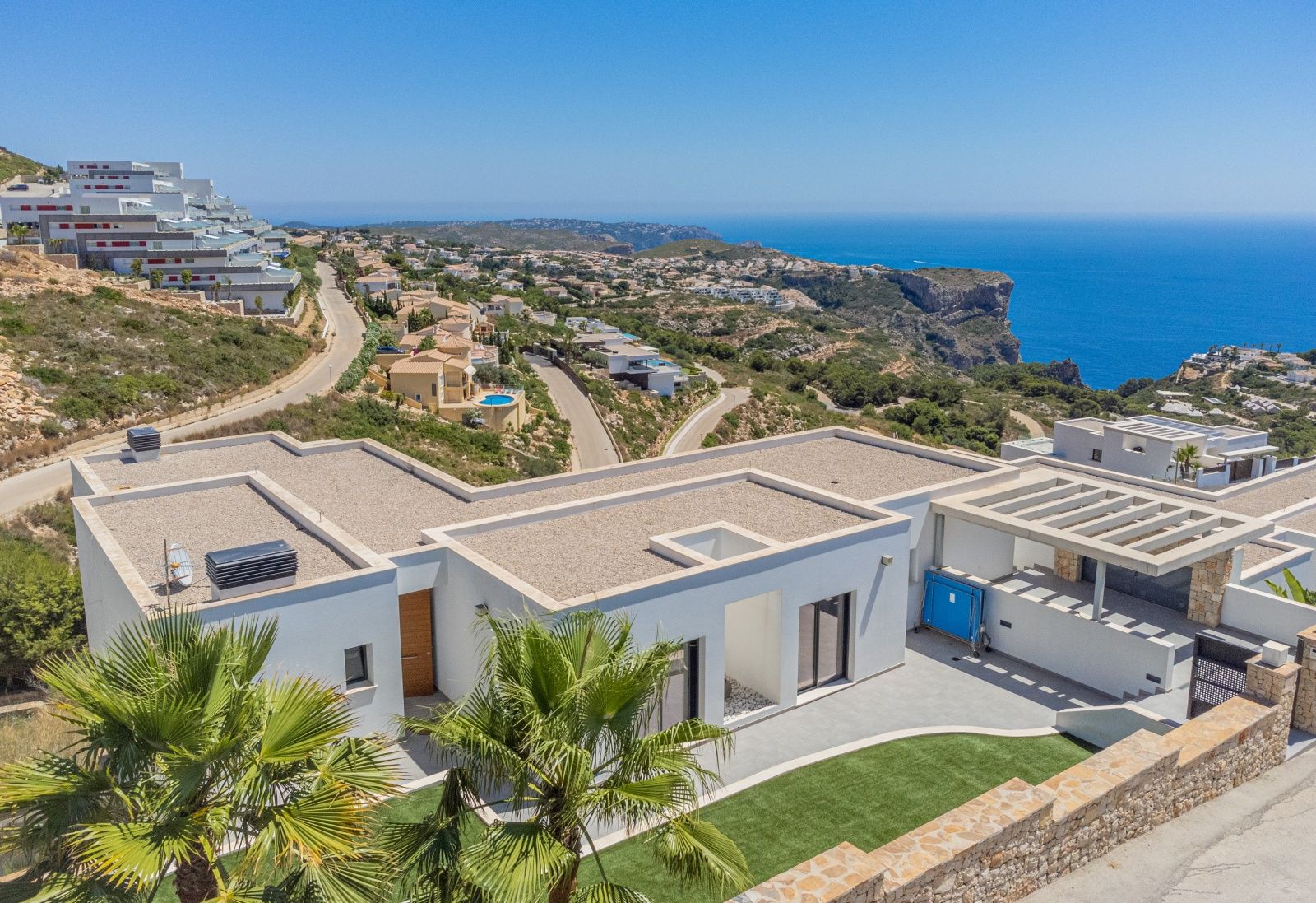 Vista aérea de la villa moderna en Cumbre del Sol, destacando su arquitectura de líneas rectas, cubiertas planas y vistas panorámicas al mar Mediterráneo y los acantilados.
