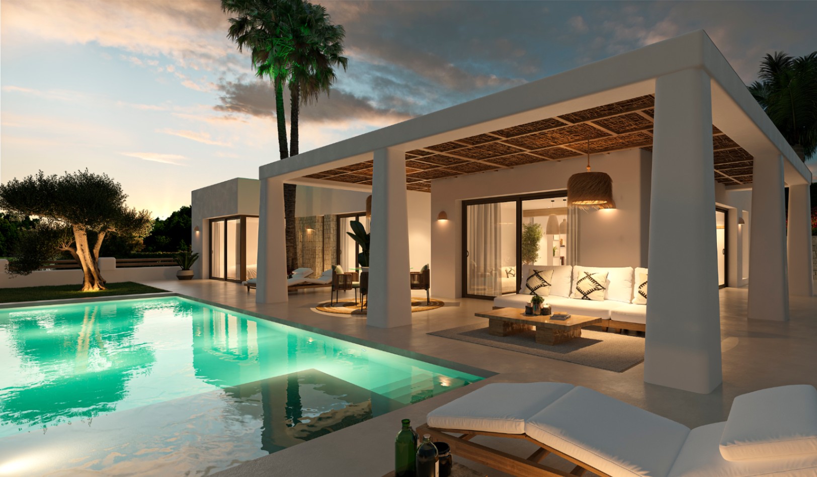 Exterior de villa estilo ibicenco con piscina iluminada, porche de vigas naturales y zona de estar al aire libre bajo un cielo de atardecer en Jávea.