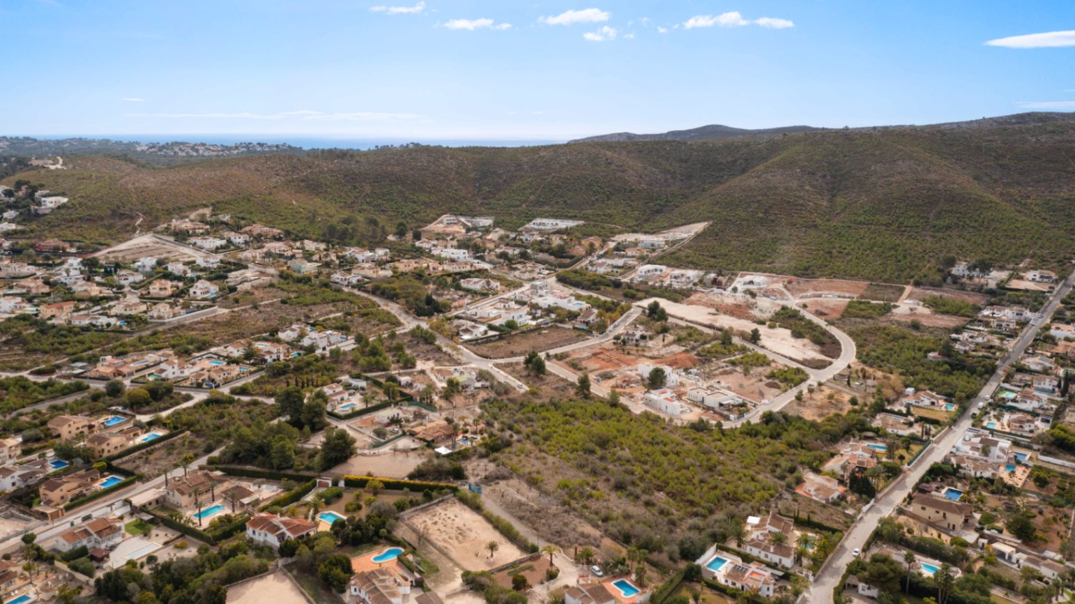 Vista aérea de la urbanización Lomas Del Rey en Jávea, mostrando la proximidad a las colinas y el mar Mediterráneo en el horizonte.