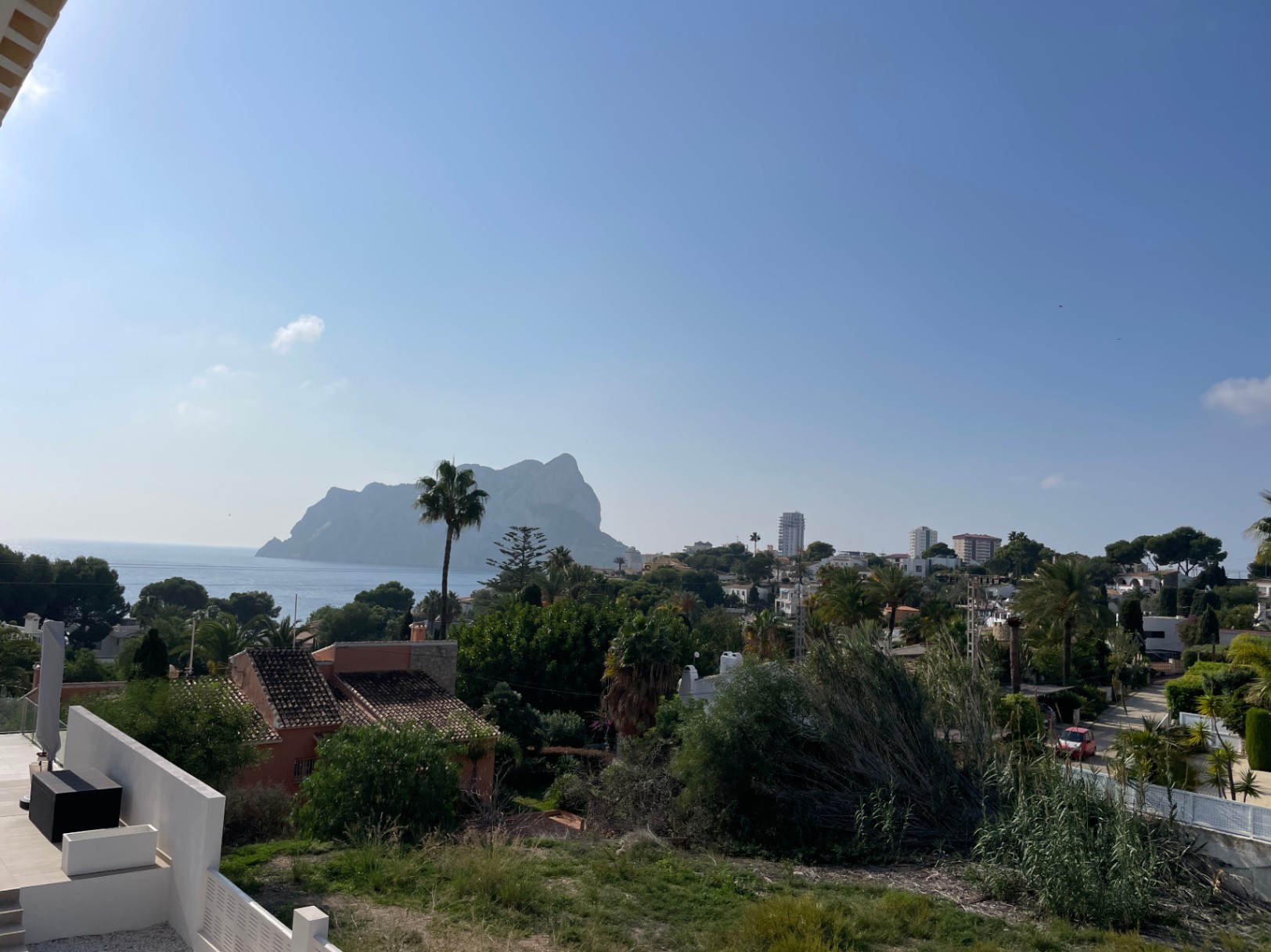 Vista panorámica del Peñón de Ifach y el mar Mediterráneo desde la parcela elevada en Bassetes, Calpe, rodeada de vegetación autóctona y viviendas unifamiliares.