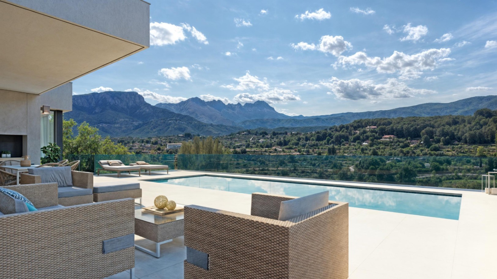 Terraza con zona de estar de ratán y piscina privada, orientada hacia las vistas panorámicas de la Sierra de Bernia con barandillas de cristal.