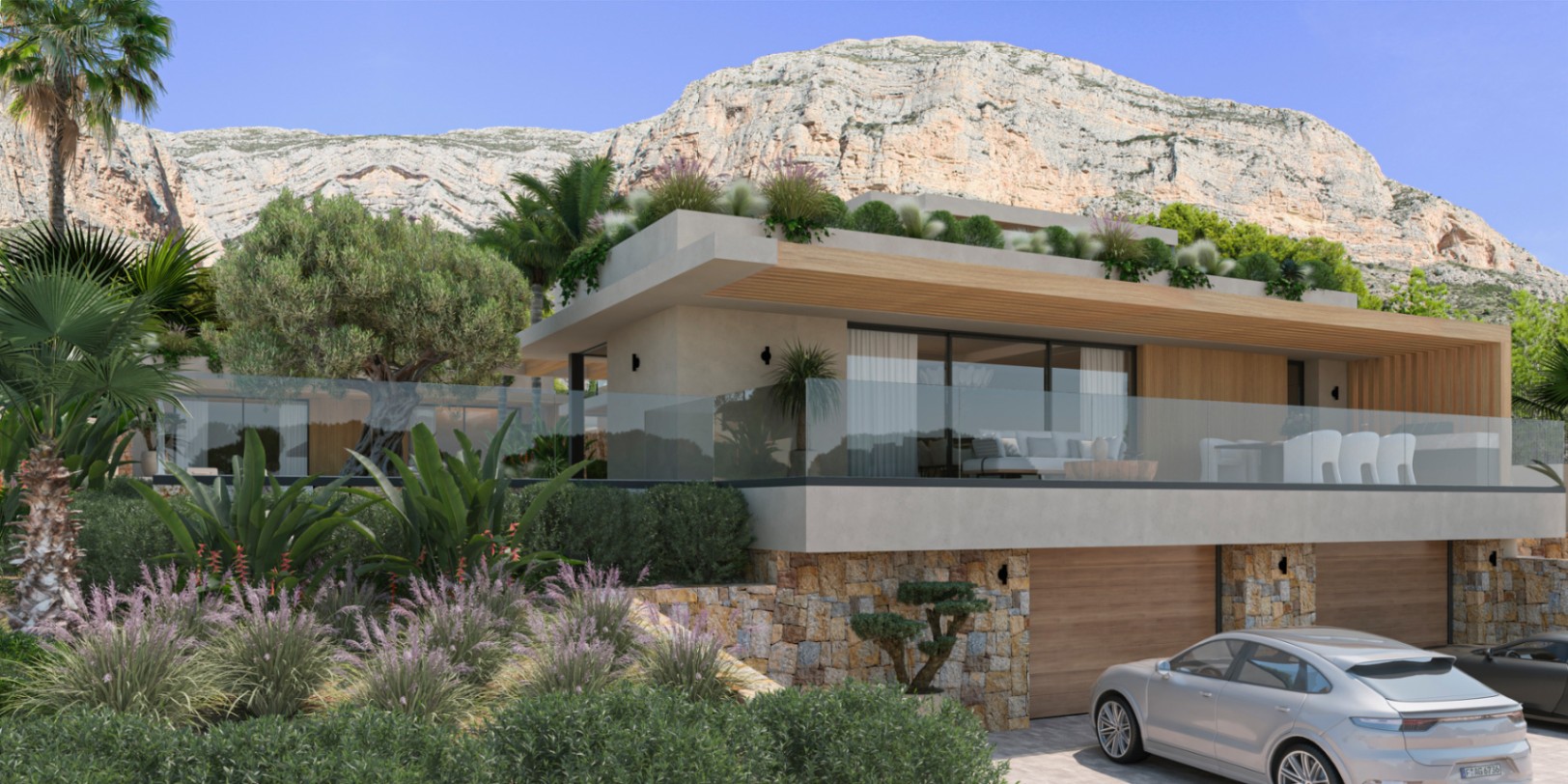 Fachada moderna con muros de piedra natural, amplios ventanales y terrazas con barandillas de cristal, situada frente al impresionante macizo del Montgó en Jávea.