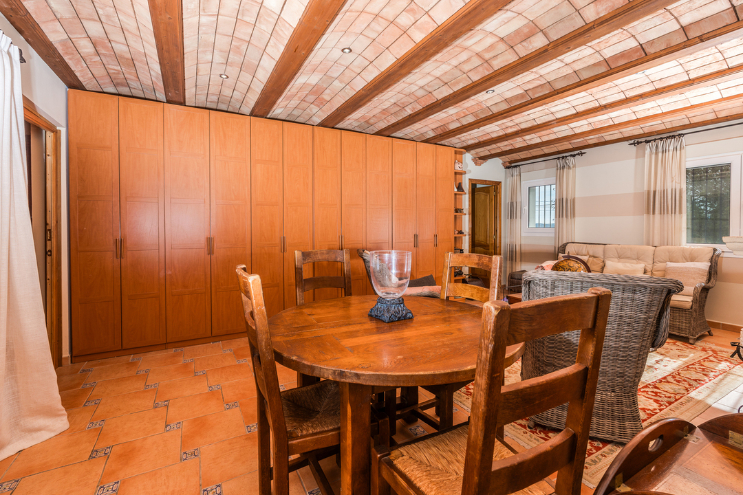 Salón comedor con techo de bóveda catalana y vigas de madera, suelo de gres rústico y un amplio armario empotrado de madera natural.