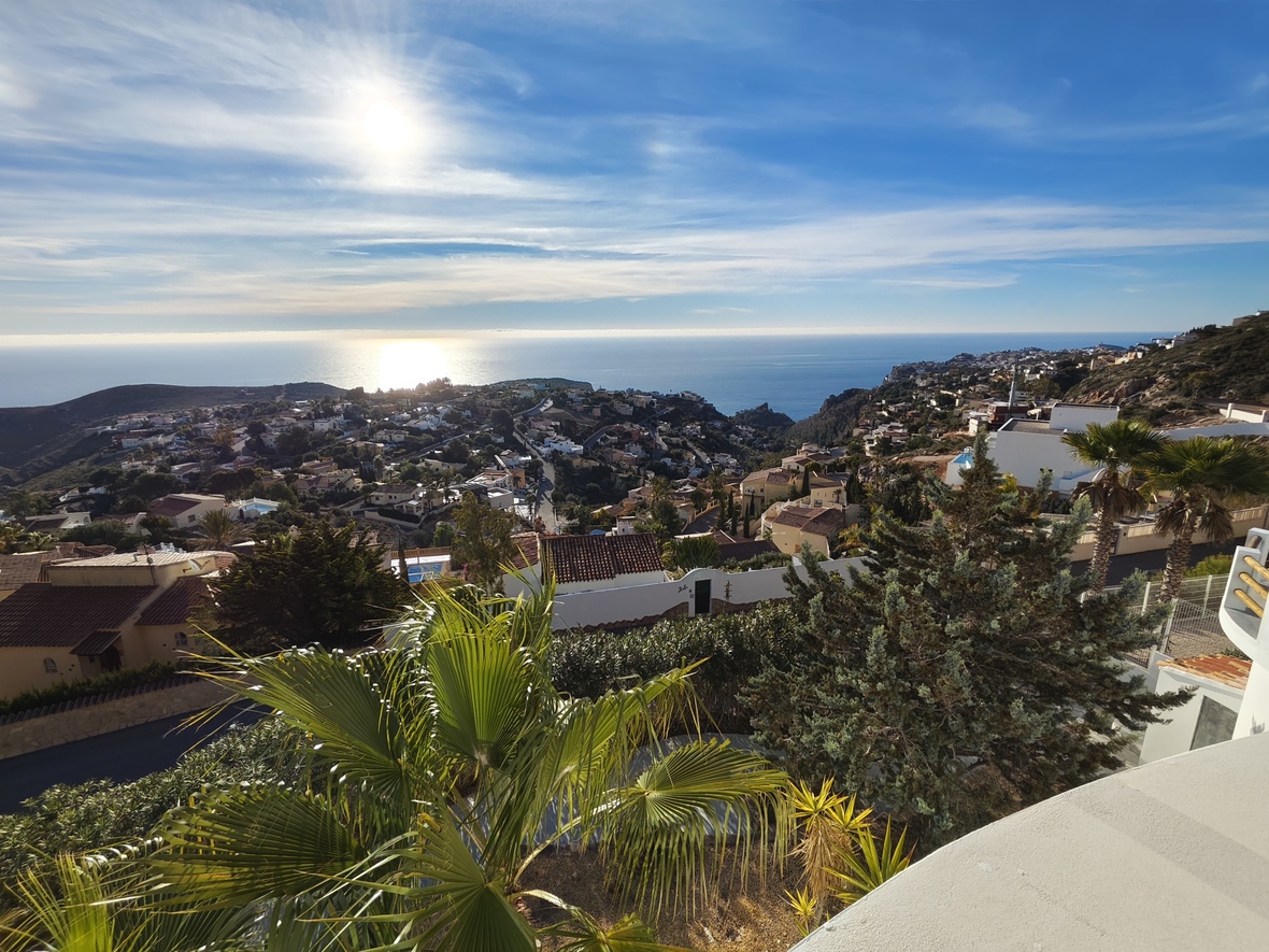 Vistas panorámicas elevadas hacia la costa y el mar Mediterráneo, con villas blancas de tejados cerámicos y vegetación autóctona bajo un sol radiante.
